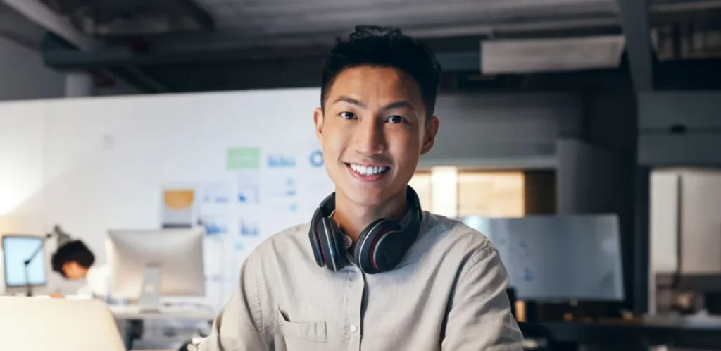 Student smiling wearing a black pair of headphones