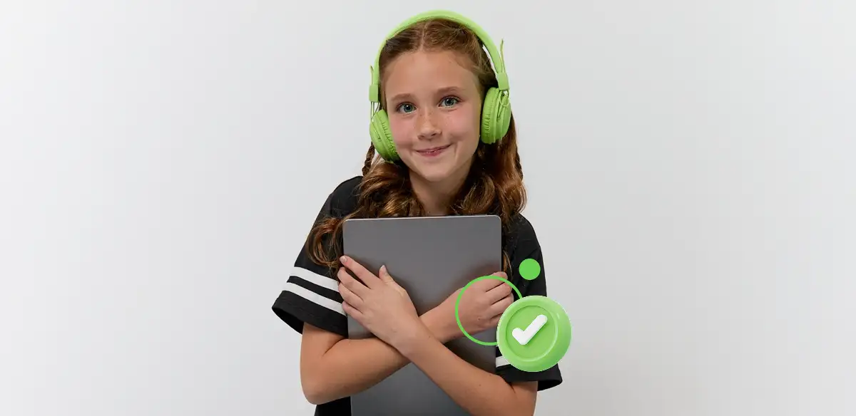 Girl wearing green headphones holding a tablet and smiling.
